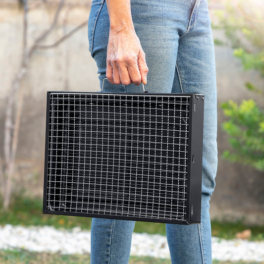 Barbacoa portátil plegable siendo transportada con una mano por su diseño compacto
