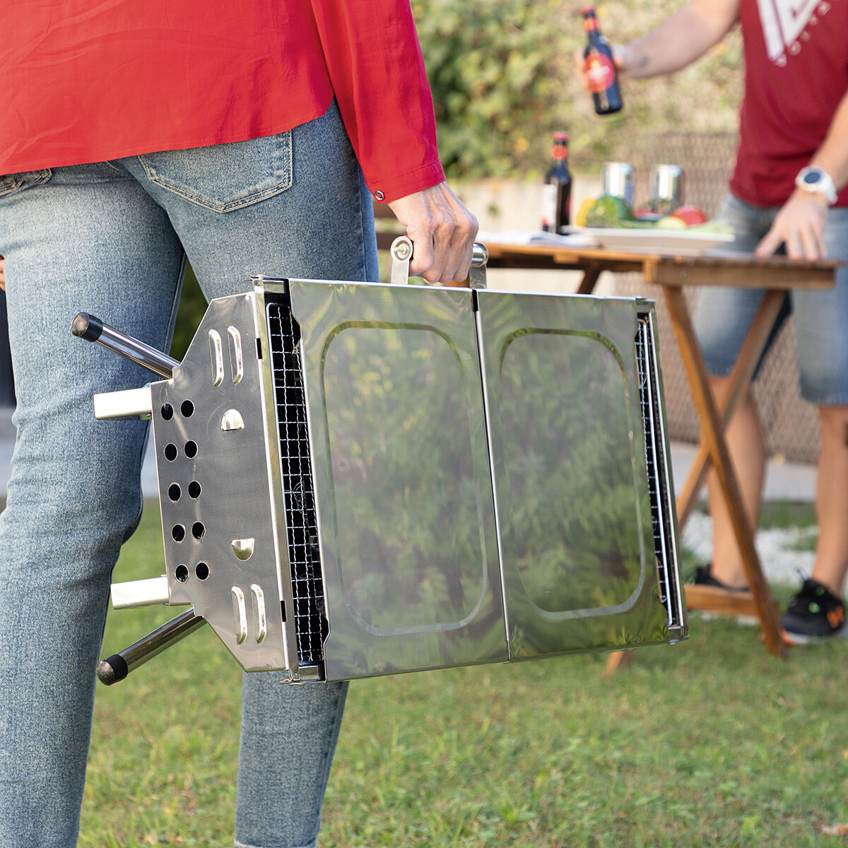 Barbacoa portátil plegable cerrada siendo transportada por su diseño compacto